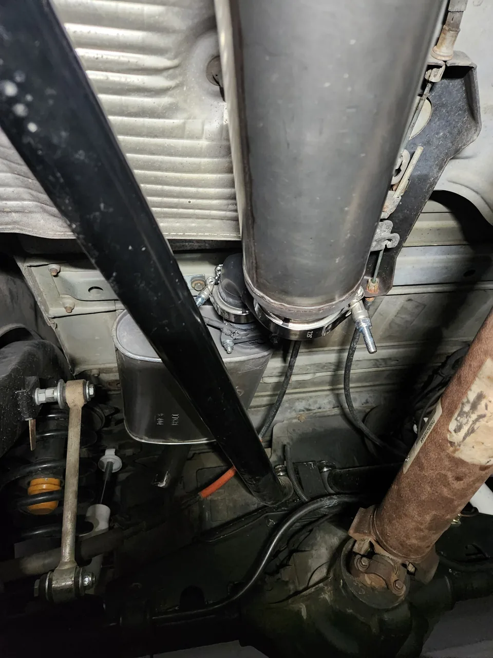 New exhaust pipe section clamped in place under a vehicle