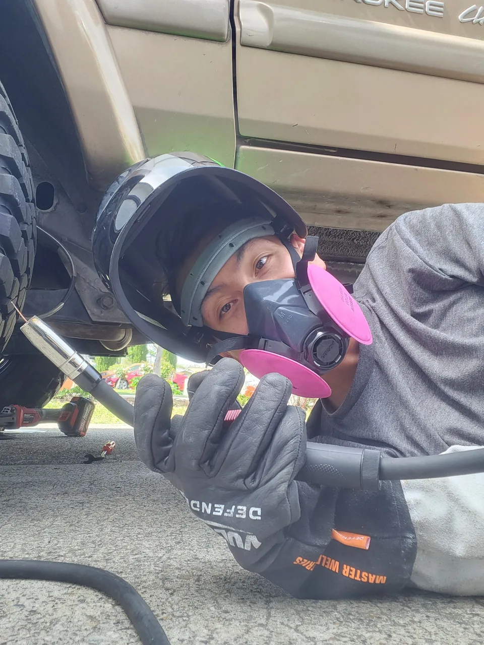 Monty working underneath a vehicle wearing a respirator