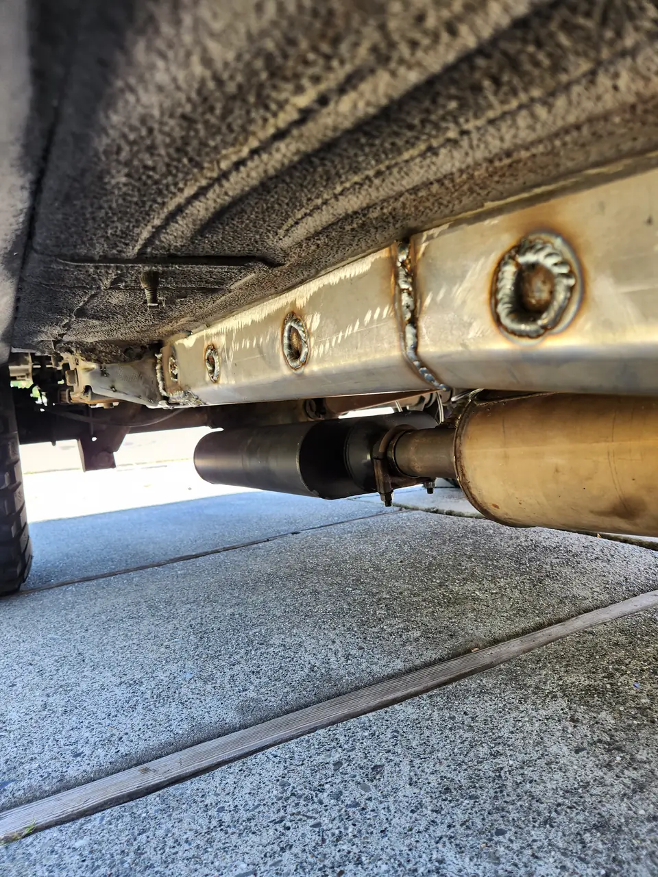 Frame rail reinforced with a welded steel plate, exhaust below